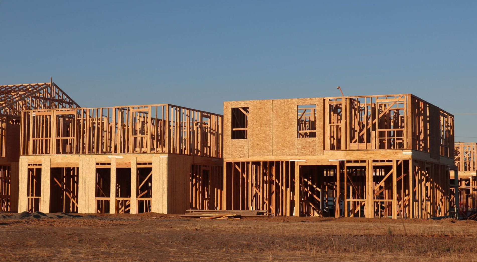 Wooden frames of new homes under construction in Elk Grove, California, during daylight.